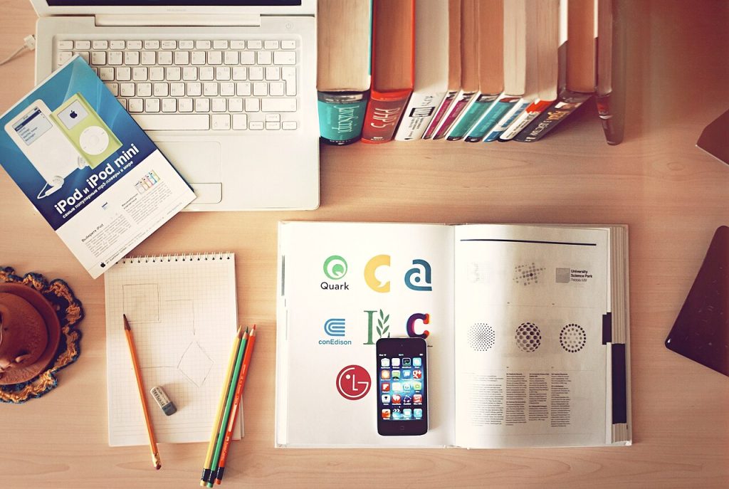 Kitap, dizüstü bilgisayar ve telefon bulunan çalışma masası